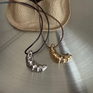 Detail view of gold and silver croissant pendants on simple black leather cords