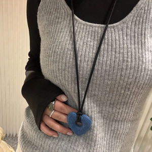 Detail of blue porous volcanic stone heart pendant on long black cord necklace
