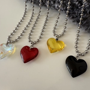 Detail of colorful heart pendants on silver ball chains in white, red, yellow, and black