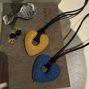 Detailed shot of textured heart pendants and logo earrings on a vintage book