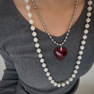 Detail of layered titanium necklaces with large red crystal heart and faux pearl beads