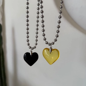Close-up of black and amber heart pendants on silver metal ball chains for women