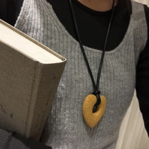 Detail of hollow heart pendant made of volcanic stone on a black cord necklace