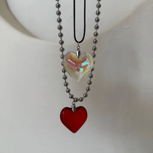 Detailed view of red and iridescent crystal heart pendants on bead chain and black cord