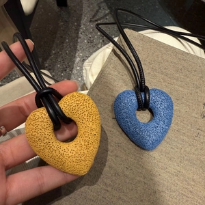 Close-up of yellow and blue heart-shaped lava stone pendants on minimalist leather cords