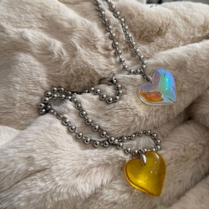 Macro view of crystal heart pendants on silver-tone bead chains against soft fur texture