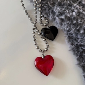 Detail view of double heart pendants in red and black on a silver metal ball chain