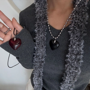 Detail of dark red and black heart pendants worn with beaded chain and cord necklaces