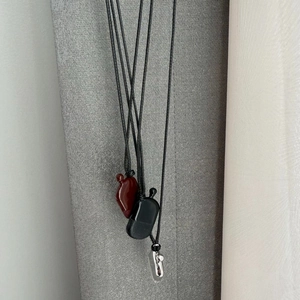 Details von Flachmann-Anhängern in Rot, Mattschwarz und Silber an schwarzen Kordelketten