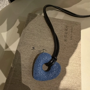 Macro detail of navy heart-shaped lava stone pendant with black minimalist leather cord