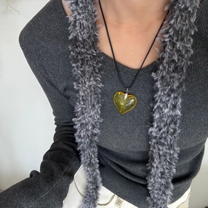 Close-up of heart-shaped yellow resin pendant necklace worn on a simple black cord