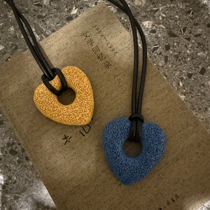 Detail showing heart-shaped volcanic stone pendants in yellow and blue with black cords
