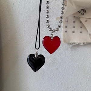 Detail of red translucent acrylic and black ceramic heart pendants on minimalist background