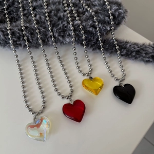 Detail view of heart-shaped crystal pendants on beaded stainless steel necklaces