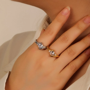 Gros plan de bagues croisées en or et argent avec zircons ronds sur la peau d'un mannequin
