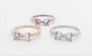 Détail de la bague nœud en or rose avec pierres en cœur et texture perle gaufrée