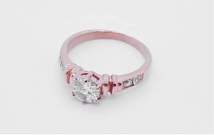 Close-up of rose gold ring with round brilliant-cut center stone and vertical grooved band