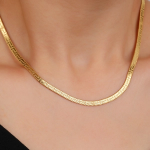 Elegant gold flat snake chain necklace with Greek meander pattern worn on neck
