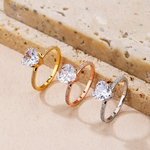 Three heart-shaped diamond rings in gold rose gold and silver on travertine stone