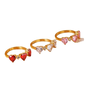 Three-stone gold ring set featuring red, white, and pink heart-shaped gemstones