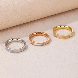 Detail of three steel rings in silver, gold, and rose gold with white shell inlay