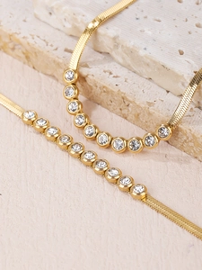 Macro detail of gold herringbone necklace and bracelet set with round cubic zirconia stones
