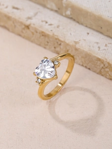 Detailed close-up of golden heart-shaped zircon ring on natural stone texture