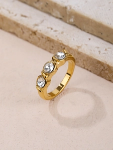 Gros plan détaillé d'une bague minimaliste dorée ornée de trois pierres de zircone
