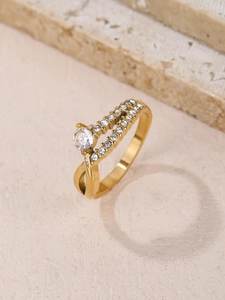 Detail of elegant gold-toned crisscross ring featuring a round center stone and pave accents