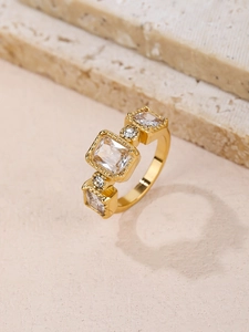 Dettaglio anello dorato con texture vintage e cinque zirconi quadrati scintillanti