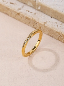 Macro shot of gold Mobius ring with sparkling zircons on elegant stone texture background