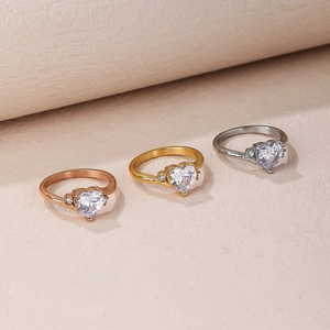 Three elegant heart-cut rings in rose gold, yellow gold, and silver finishes displayed