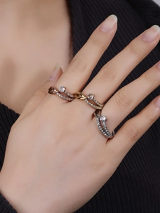 Close-up of stacked three-tone intertwined rings with pavé diamonds and crystals