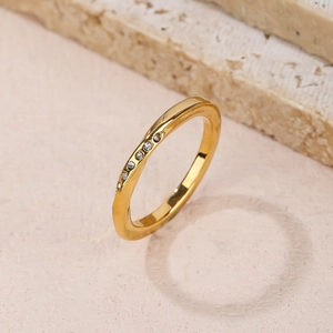 Minimalist gold Mobius ring with seven inlaid zircons on a textured stone background