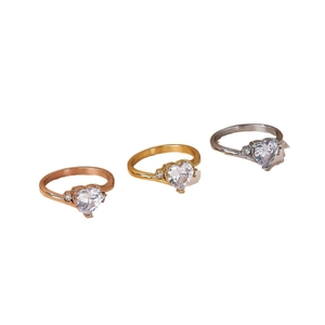 Three minimalist heart-shaped rings in rose gold, gold, and silver with zircon accents