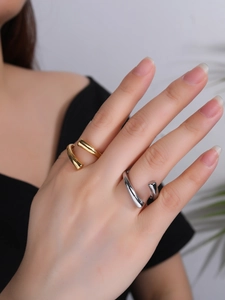 Detailed view of layered gold and silver rings with a minimalist open-wrap design