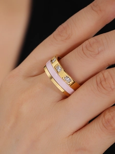 Detailed close-up of a gold-plated ring with pink enamel and three inset rectangular crystals