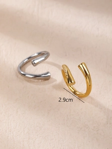 Close-up of minimalist gold and silver 2.9cm C-shaped rings on textured background