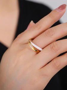 Close-up of double-layered gold and white ceramic ring with three sparkling diamonds