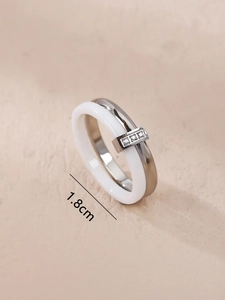 Close-up of white ceramic and silver stainless steel double ring with zircon stones