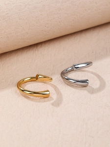 Close-up of minimalist streamlined C-shaped rings in polished gold and silver mirror finish