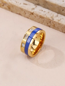 Detail view of blue enamel gold ring with three square zircons on stone background