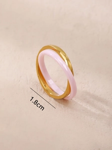 Detail view of interlocking gold metal and pink ceramic rings with 1.8cm inner diameter