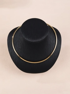 Choker dorato lucido esposto su busto nero su sfondo beige dallo stile moderno
