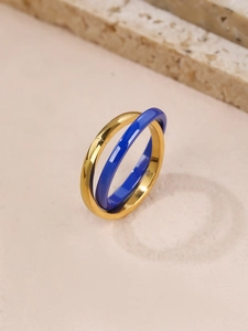 Detail view of interlocking gold metal and dark blue ceramic rings on a textured background