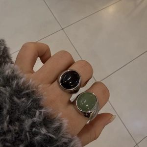 Dettaglio di anelli vintage con pietre naturali ovali nere e verdi su fascia in argento