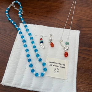Detail of beaded necklace and bird pendant set with blue agate on white fabric