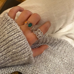 Nahaufnahme von Harzring mit Steinen und silbernem Gitterring am Finger getragen