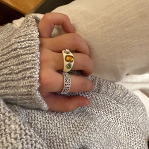 Nahaufnahme eines weißen Harzrings mit Edelsteinen und einem silbernen Zirkonia-Band
