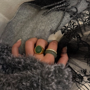Dettaglio del set di anelli dorati con pietra naturale verde e fascia di cristalli sulla mano